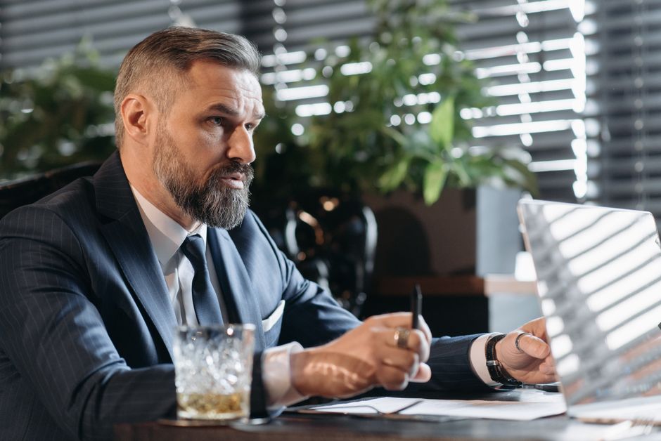 スーツを着たひげのある真剣なビジネスマンが、室内でのプロフェッショナルな会議中に集中しています。