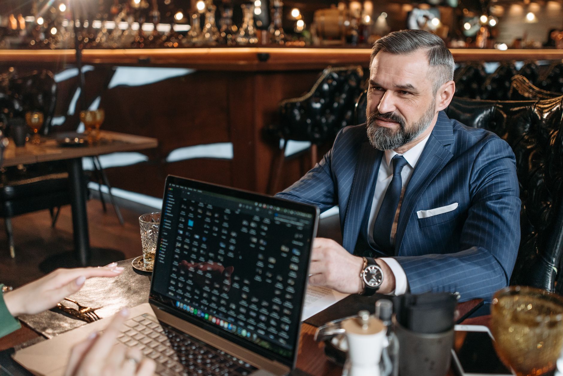 Businessman discussing work on a laptop during a meeting in a stylish coffee shop environment.
