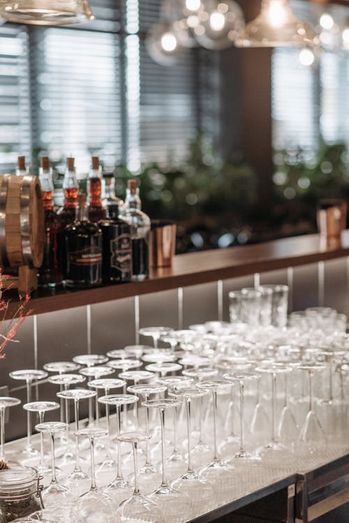 Clean Glasses and Bottles of Alcohol Standing on a Bar Counter 