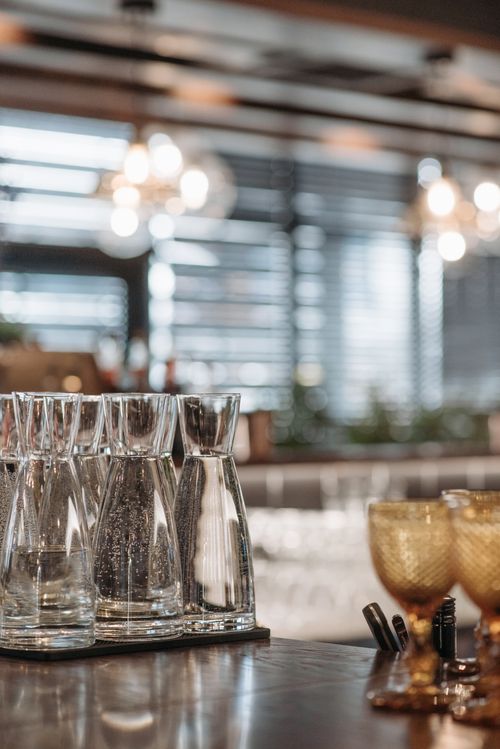 Free Stylish bar counter with empty glass carafes and ornate goblets, perfect for modern dining settings. Stock Photo