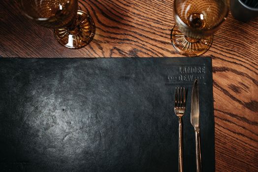 Top-down view of an elegant table setting with wine glasses and cutlery on a wooden table.