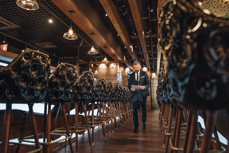 A Man Walking Inside A Restaurant Holding Some Documents