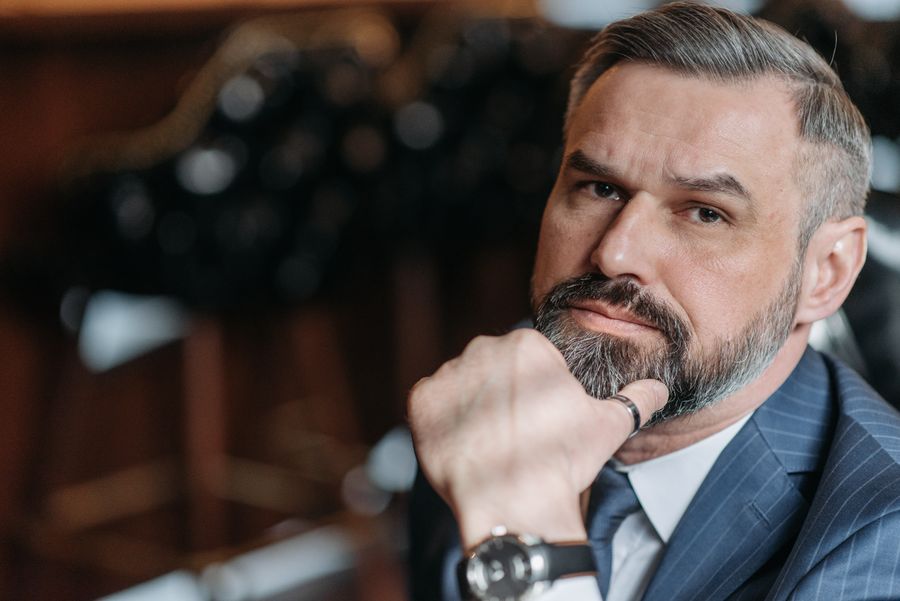 An older man with a grey beard in a dark suit