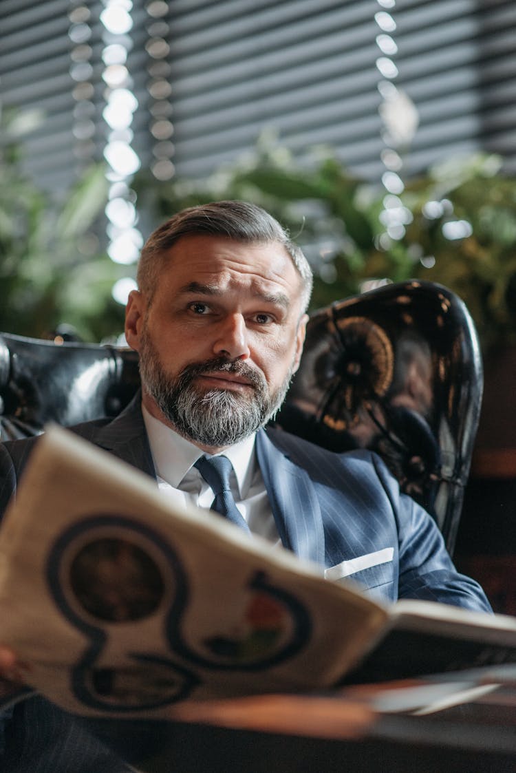 Adult Man In Blue Suit Holding A Magazine 