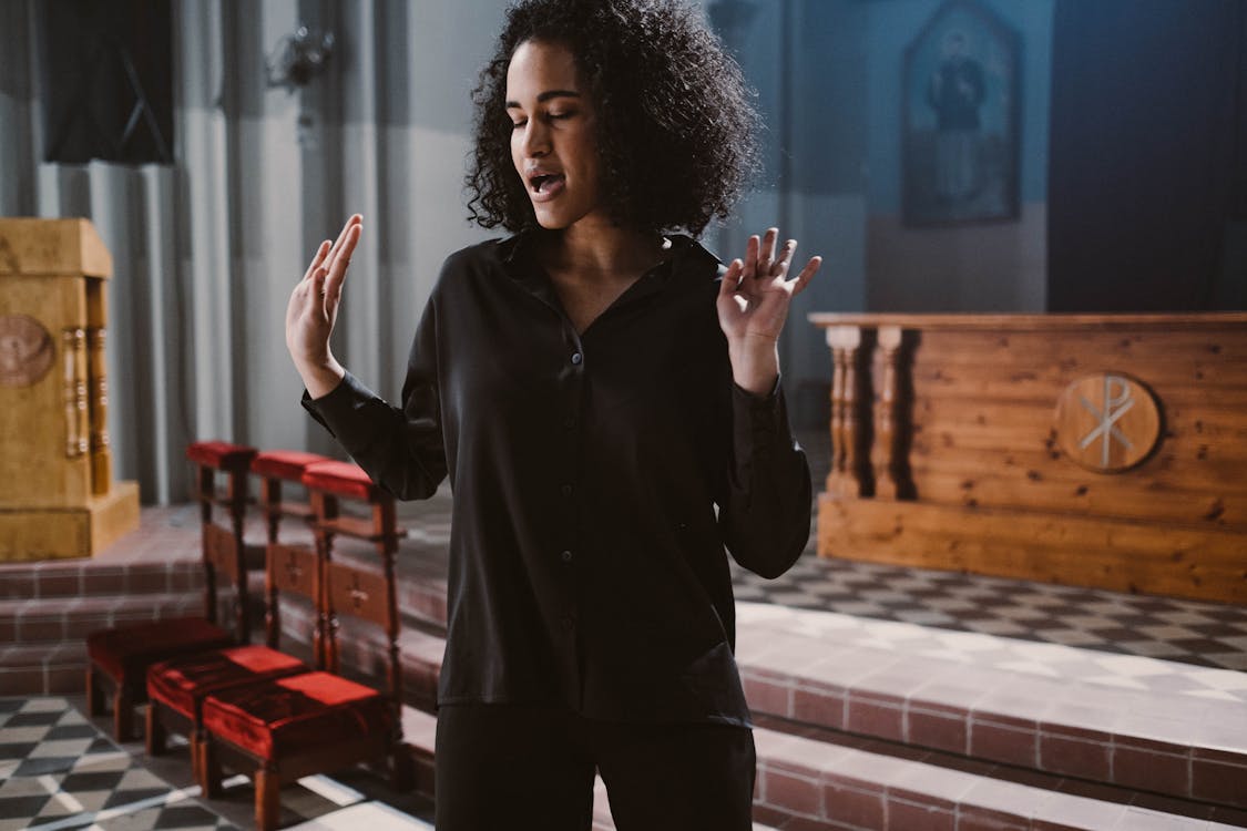 Free Woman in Black Long Sleeves Standing Near the Altar Stock Photo