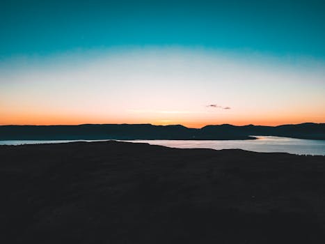 Stunning sunset view over a tranquil river and silhouette of the Scottish Highlands.
