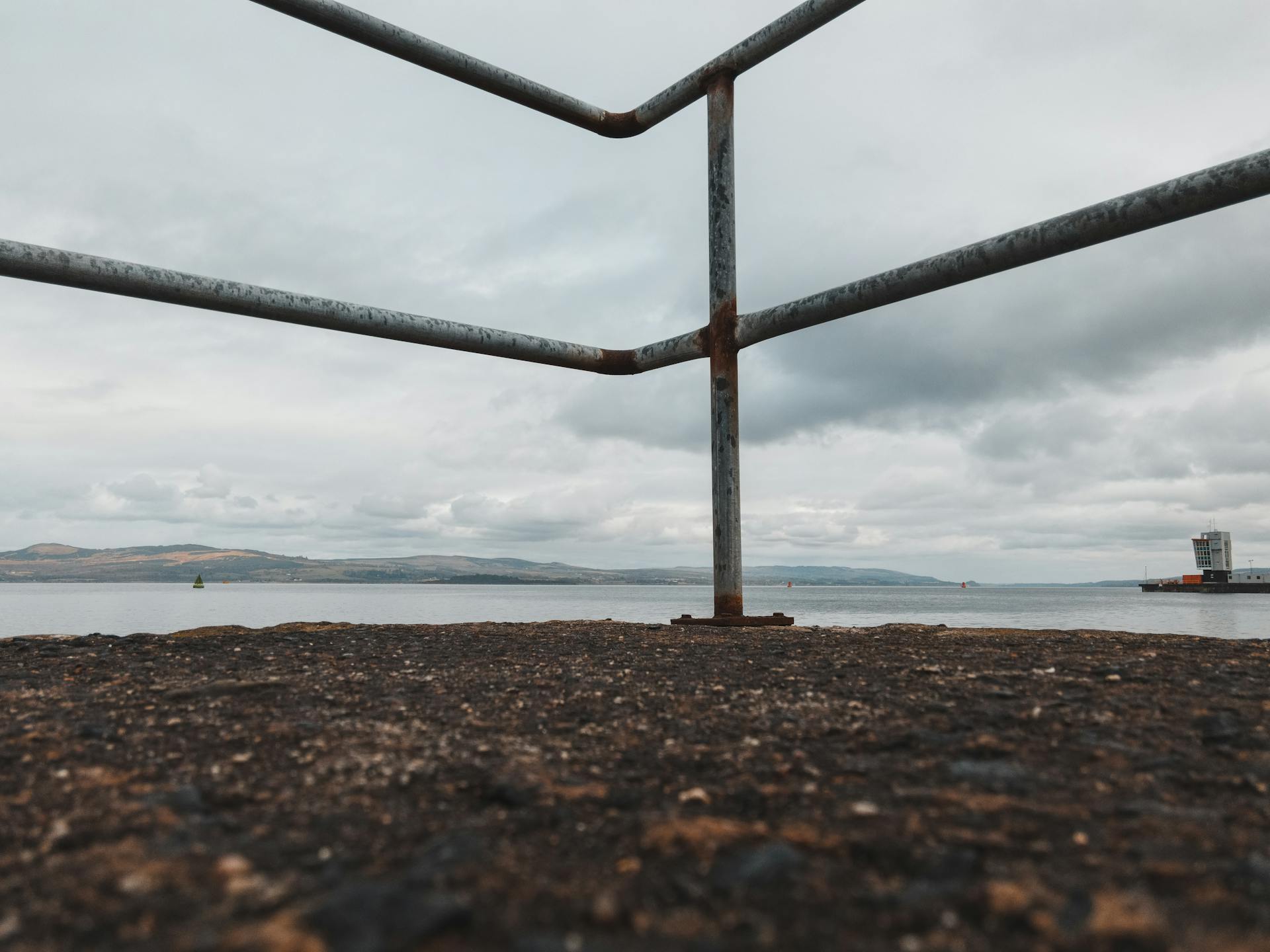 Low angle view of rusty steel railings at a dock in Greenock, Scotland overlooking the sea.