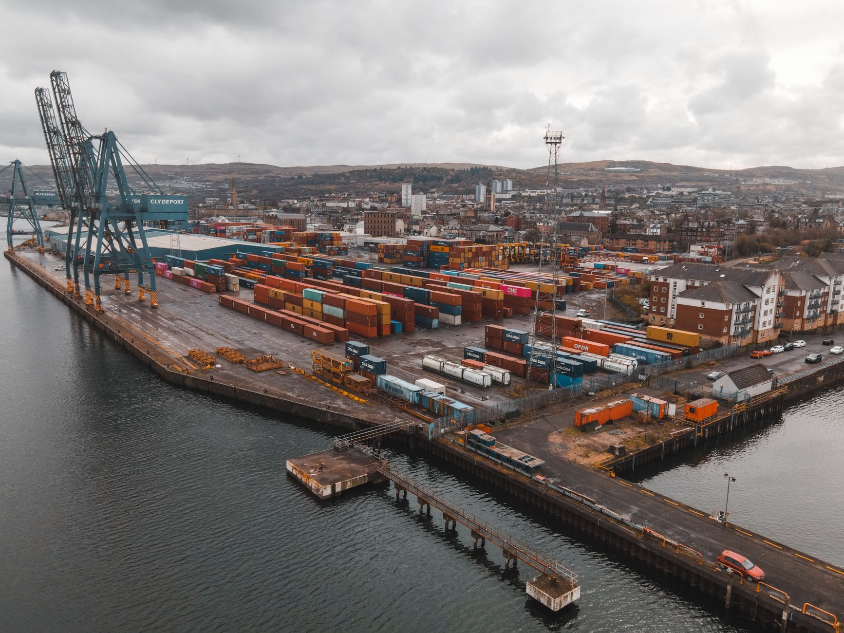 Aerial view of Greenock Harbor showcasing shipping containers and infrastructure in Scotland.