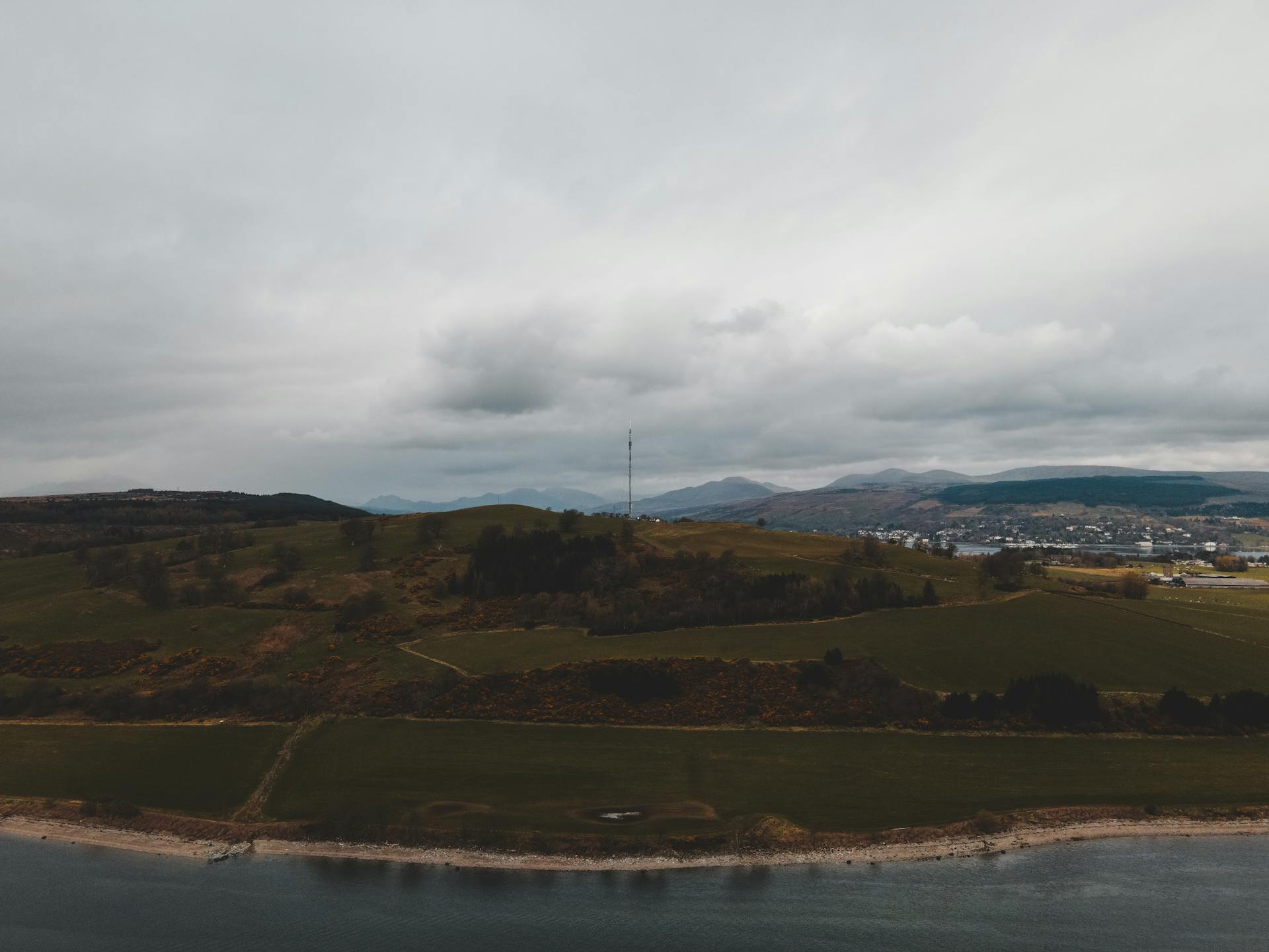 Aerial shot capturing the scenic hills and coastline of Greenock, Scotland with overcast skies.