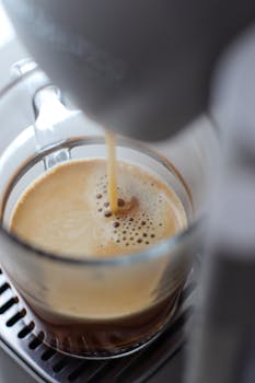 Close-up view of freshly brewed espresso pouring into a glass cup from a coffee machine.