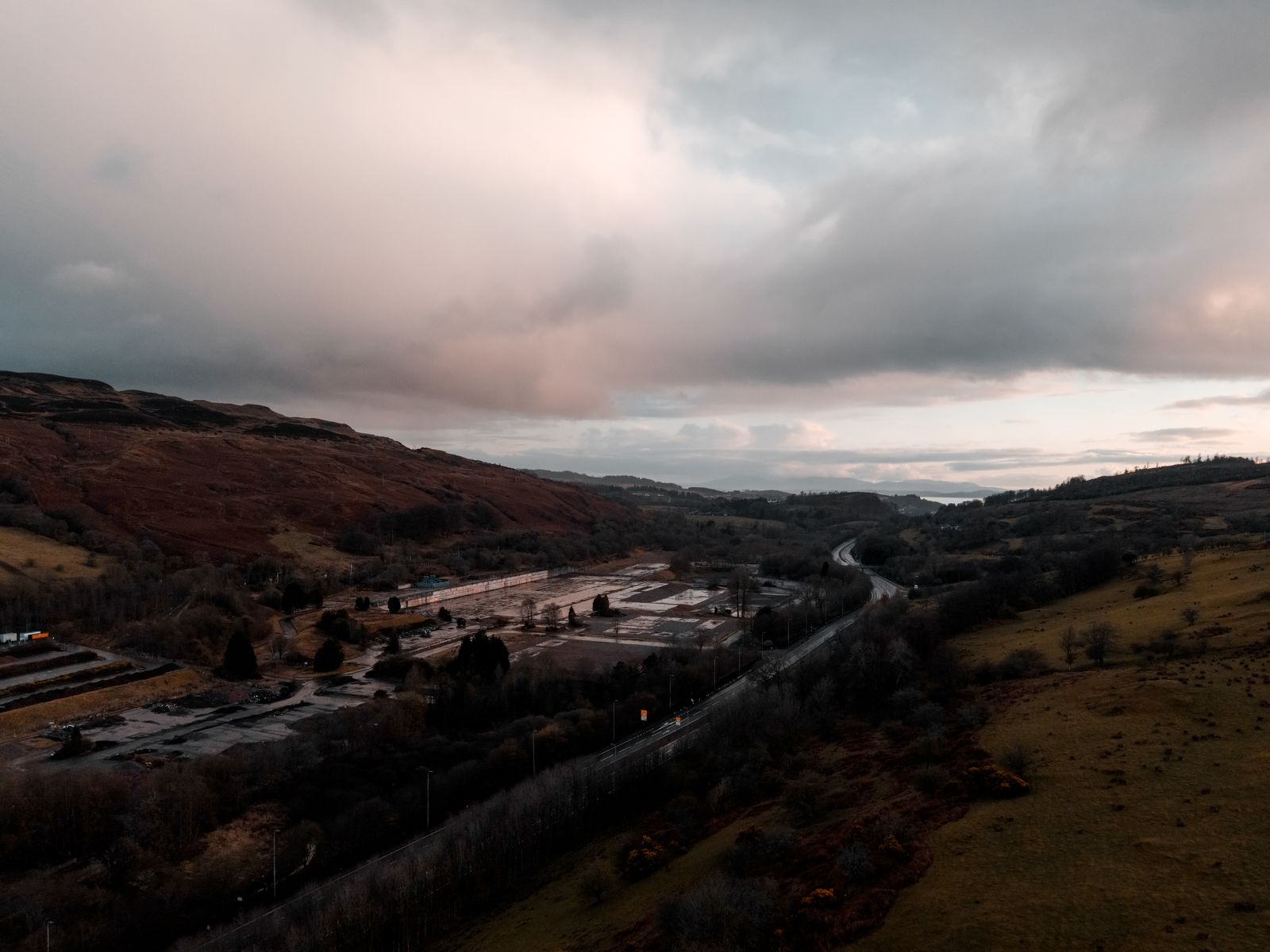 Scottish Highlands landscape with dramatic clouds and winding road through rolling hills