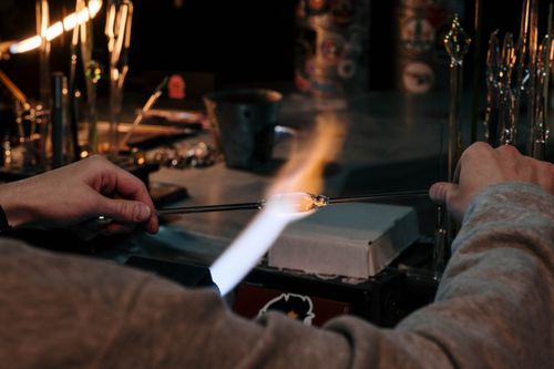 Free Artisan skillfully crafting glass with a blowtorch in a workshop environment. Stock Photo