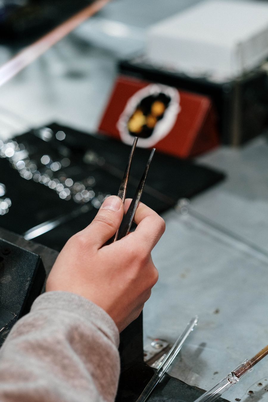 Artisanal hand using tweezers for precise crafting