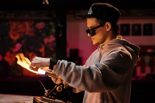 Free A focused artisan in a workshop, meticulously shaping glass with heat and precision. Stock Photo