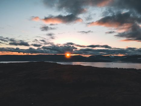 Captivating sunset over a Scottish coast with dramatic clouds and serene waters.
