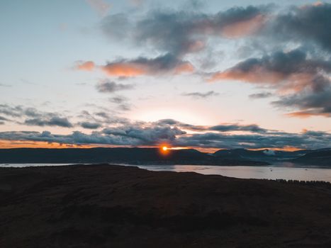 Breathtaking view of a Scottish coastline with a vibrant sunset over the sea and hills.
