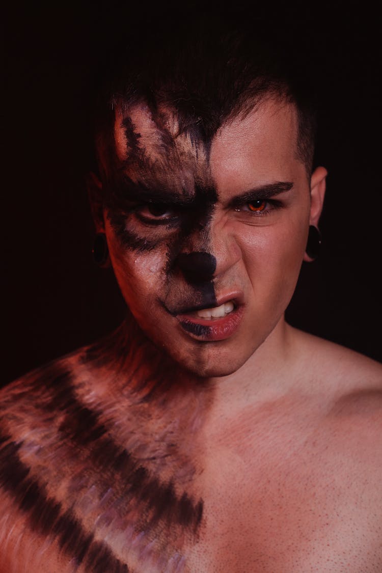 A Shirtless Man With Wolf Makeup Snarling