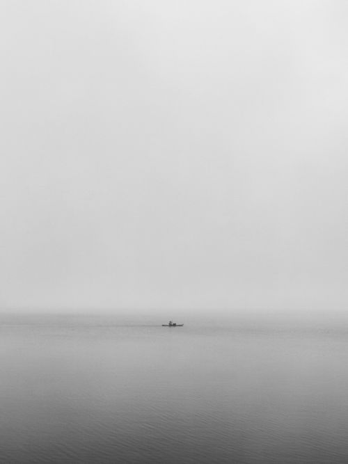 Free A lone fisherman on a boat amidst a foggy, serene lake in Zarwad Bk, India. Stock Photo