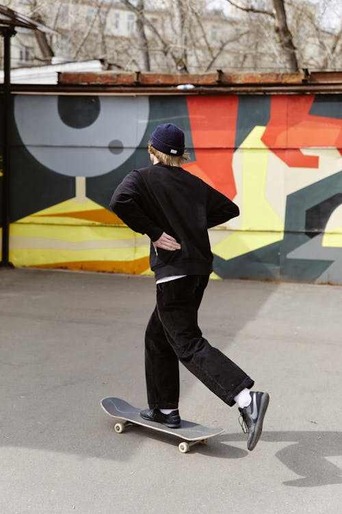Free Person in Black Sweater and Black Pants Riding a Skateboard  Stock Photo