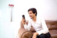 Man Smiling While Looking at his Smartphone