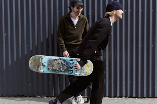 Two young men having fun with a skateboard against a black wall, capturing a casual street vibe.