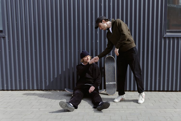 Men With Skateboard Near The Corrugated Metal Sheet Wall