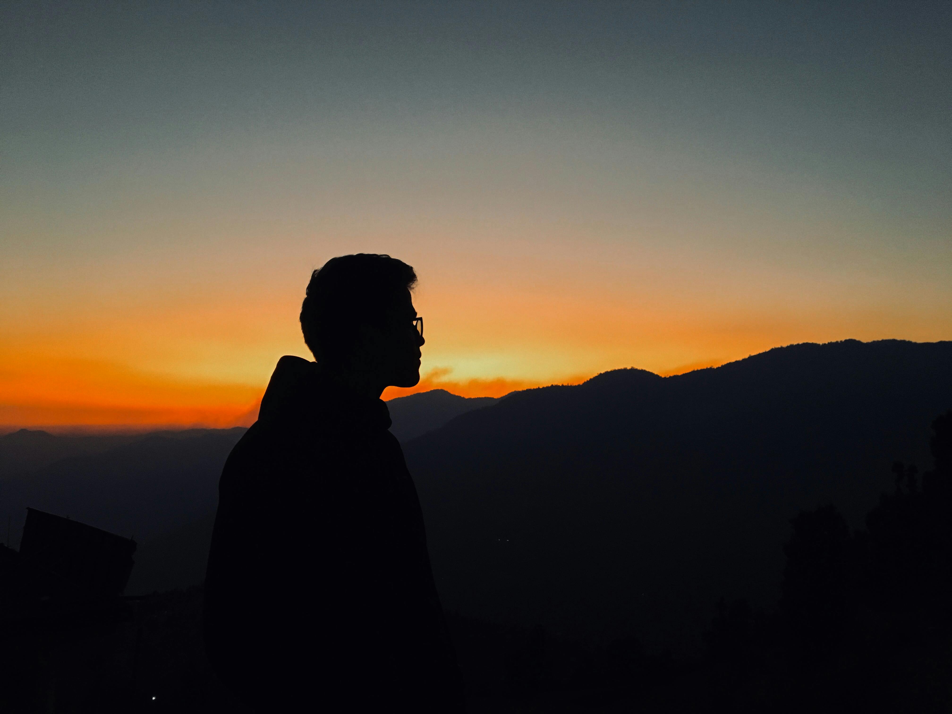 A striking silhouette against a vibrant sunset in Chamoli, India highlighting mountainous beauty.