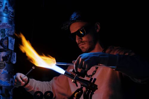 Free Artisan skillfully shaping glass using a high-temperature flame in a workshop. Stock Photo