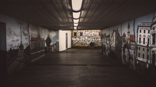 Explore an artistic underground walkway adorned with vibrant graffiti and urban murals.