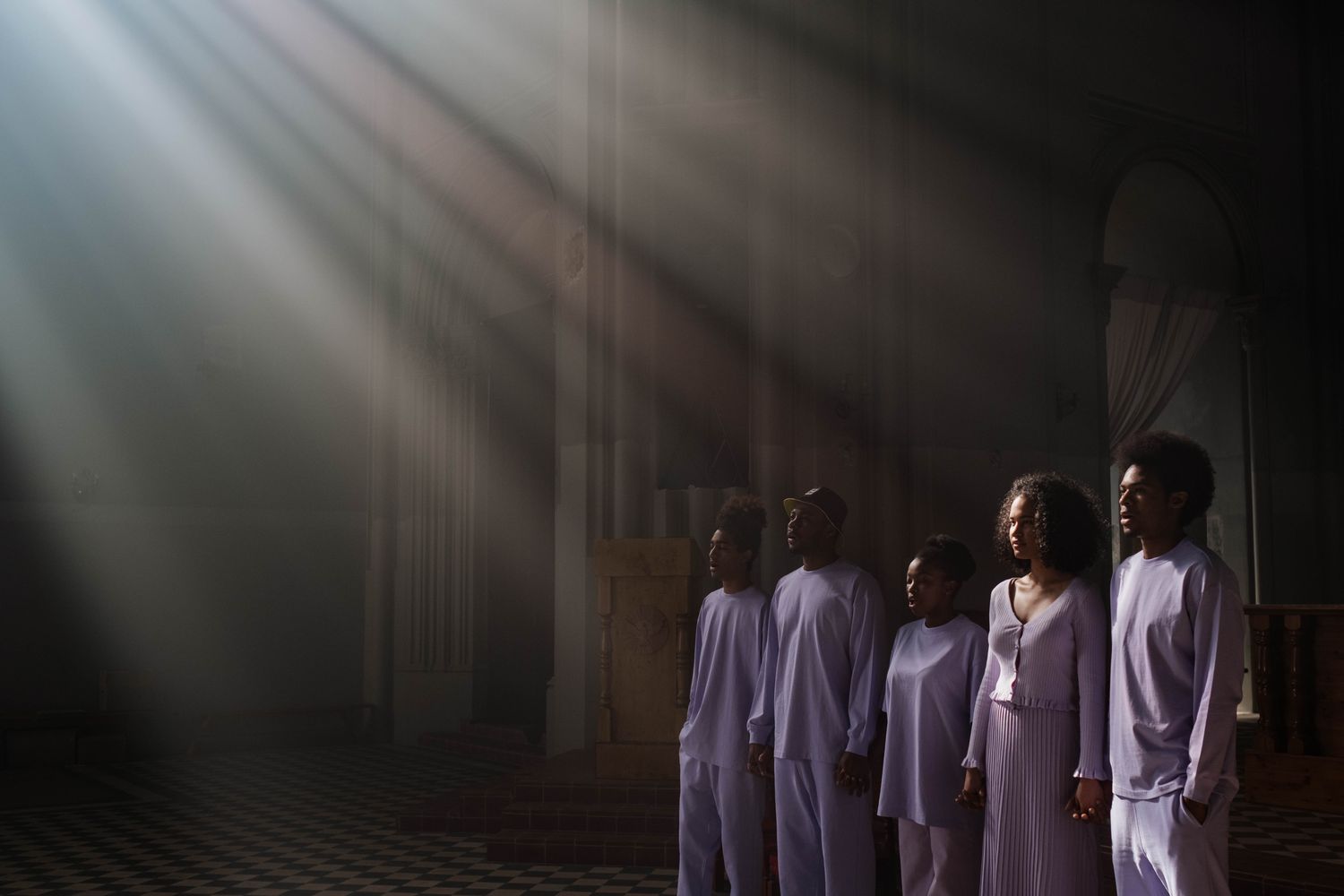 A choir of adults singing under sunbeams in a cathedral