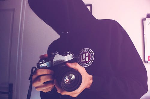 Man Holding Black and Gray Dslr Camera Inside White Wall Paint Room