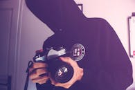 Man Holding Black and Gray Dslr Camera Inside White Wall Paint Room