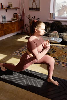 Woman engaging in yoga exercise indoors with natural sunlight streaming in.