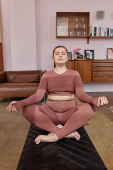 Woman practicing yoga at home, promoting a serene and healthy lifestyle.