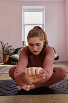 Caucasian woman practicing yoga indoors, focusing deeply during a stretching routine.