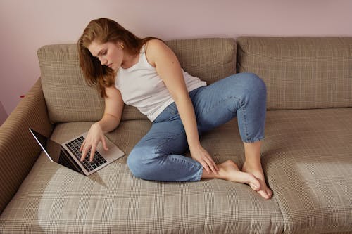Free A Woman Using Her Laptop while on the Couch Stock Photo