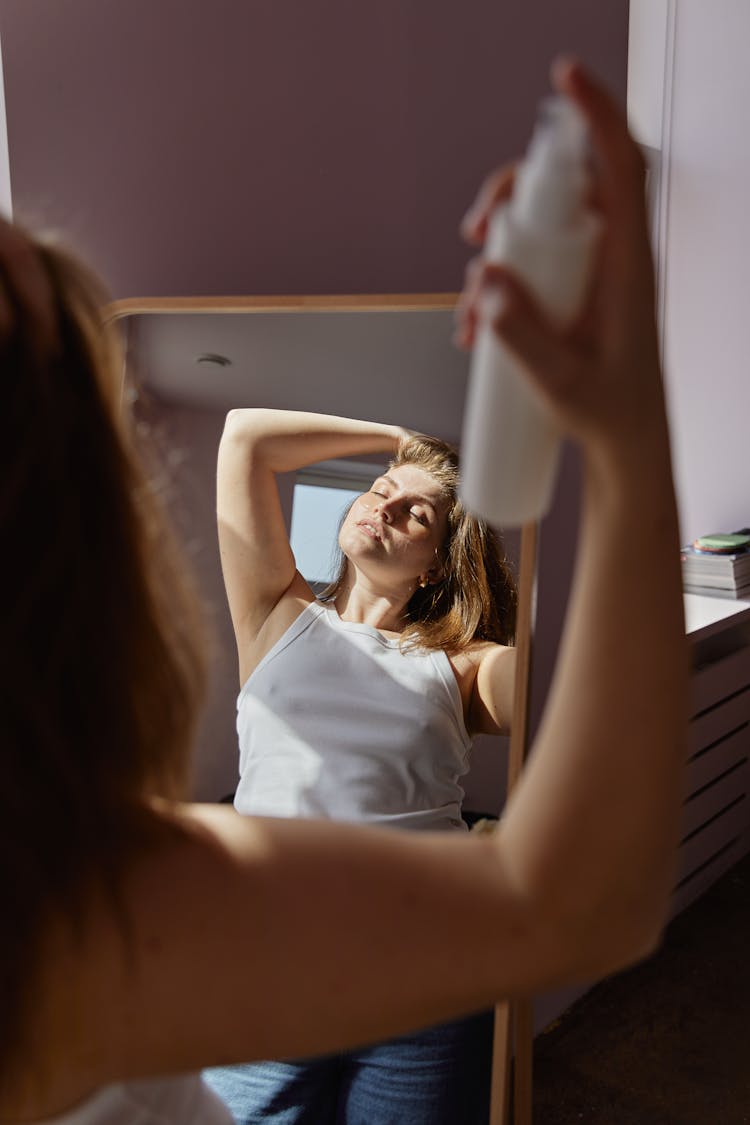 Woman Spraying Liquid On Her Hair 