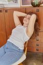 Woman in White Tank Top Sitting on Wooden Chair
