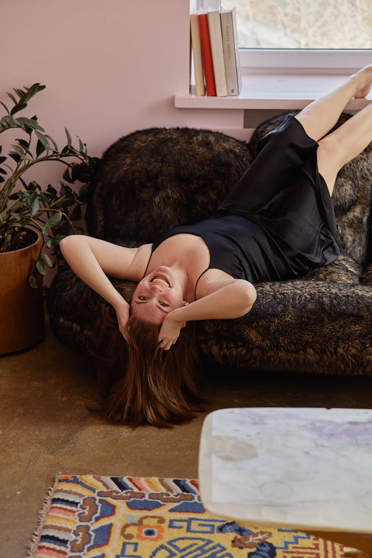 A Woman Lying Upside Down On A Furry Couch