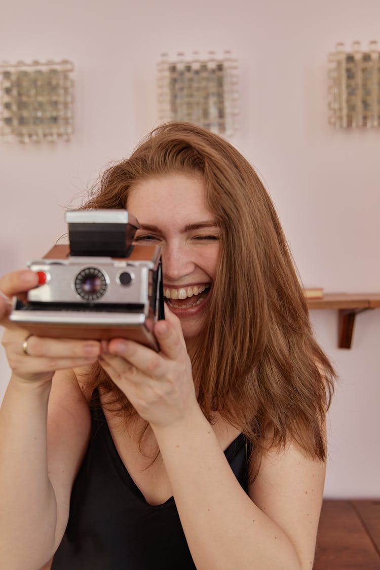 Laughing Woman Using A Vintage Polaroid Camera