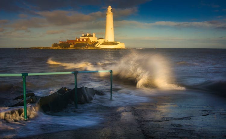 Long Exposure Of Splashing Sea Wave With A Lighthouse In The Background