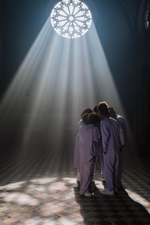 Free Choir group standing under dramatic light beams in a cathedral setting. Stock Photo