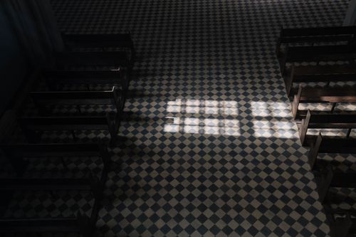 Free Sunlight casts geometric patterns on a church's tiled floor viewed from above. Stock Photo