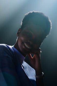 A beautiful portrait of a woman with afro hair smiling in soft daylight indoors.