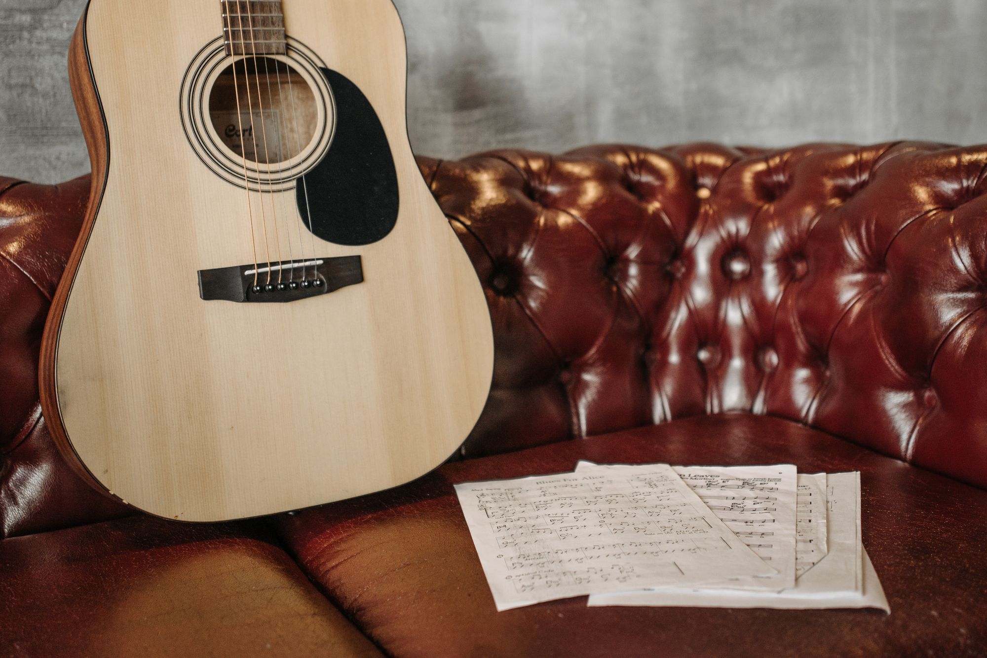 Guitarra acústica recargada sobre un sofá en una sala con luz natural