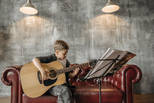Kostenloses Stock Foto zu akustische gitarre, couch, gitarrist