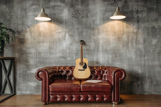 A stylish interior design featuring an acoustic guitar resting on a red leather sofa with pendant lighting.