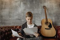Man in Black Long Sleeve Shirt Sitting on Chair While Reading Book