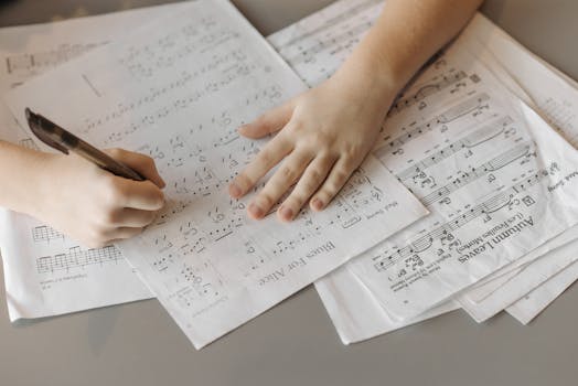 A child writes on sheet music, enhancing creativity through music composition.