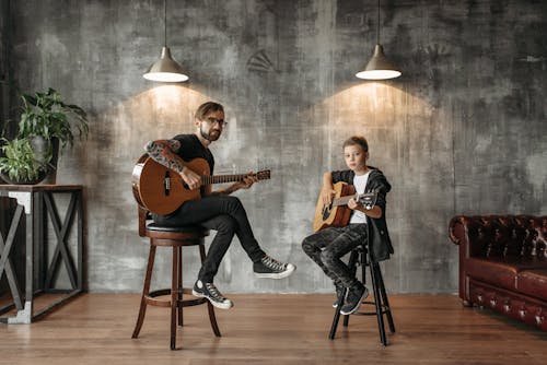 A Man and a Boy Holding Acoustic Guitars